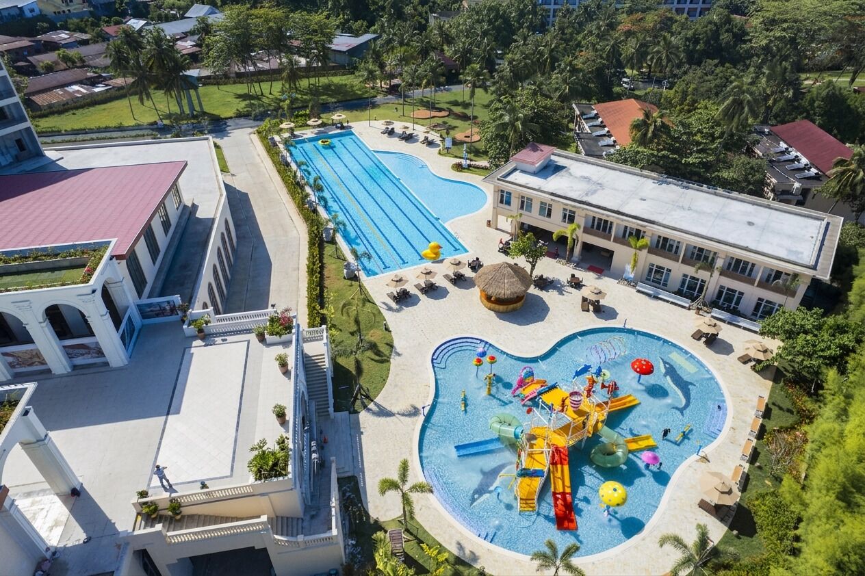 Un hotel con piscina, zona de parque acuático y un edificio de techo rojo.