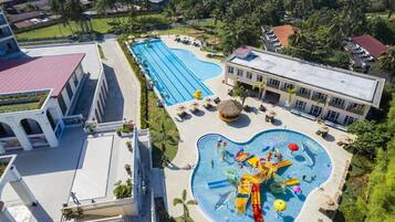 Un hotel con piscina, zona de parque acuático y un edificio de techo rojo.