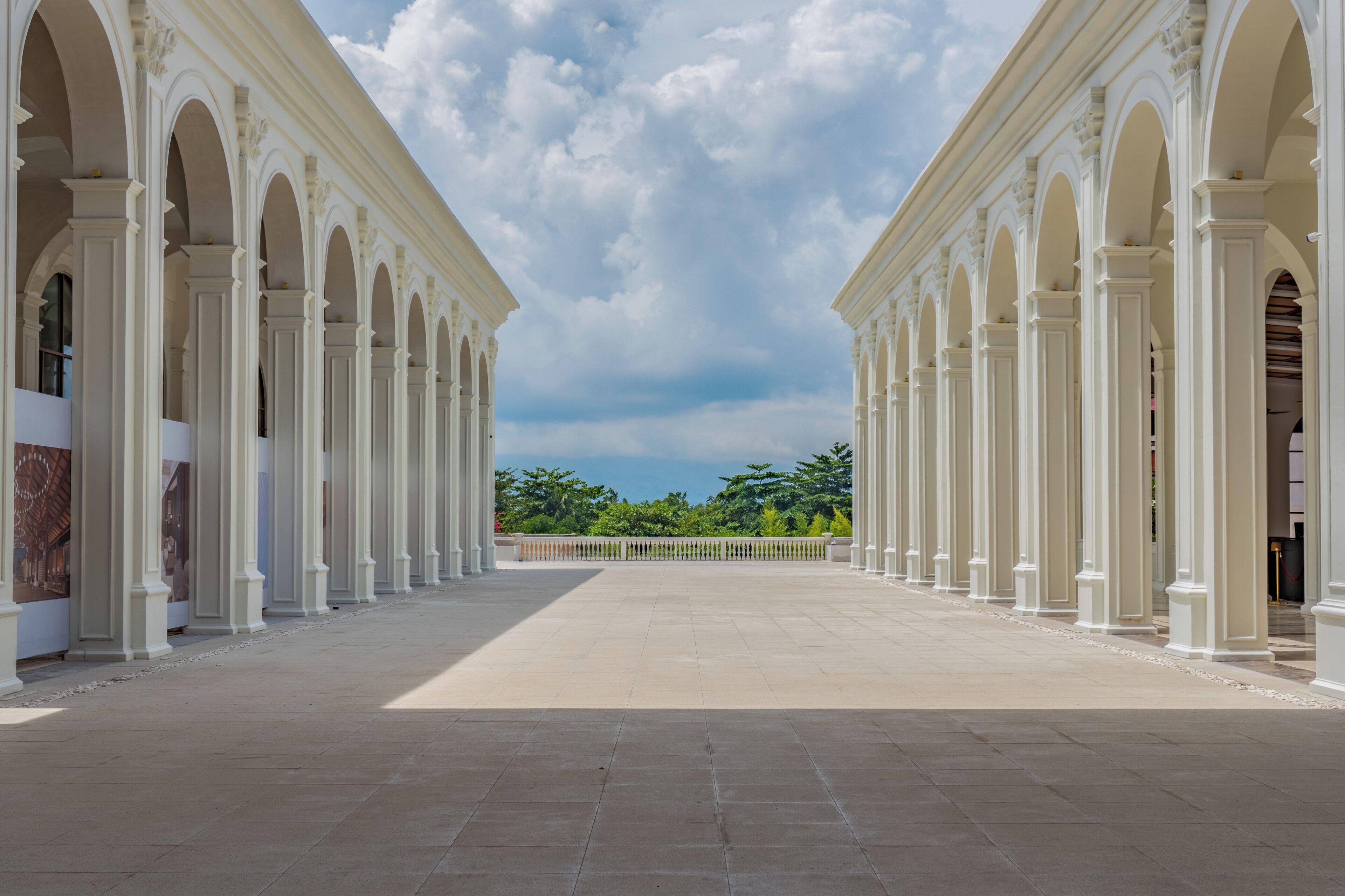 A spacious courtyard with white columns and a clear view of the sky.