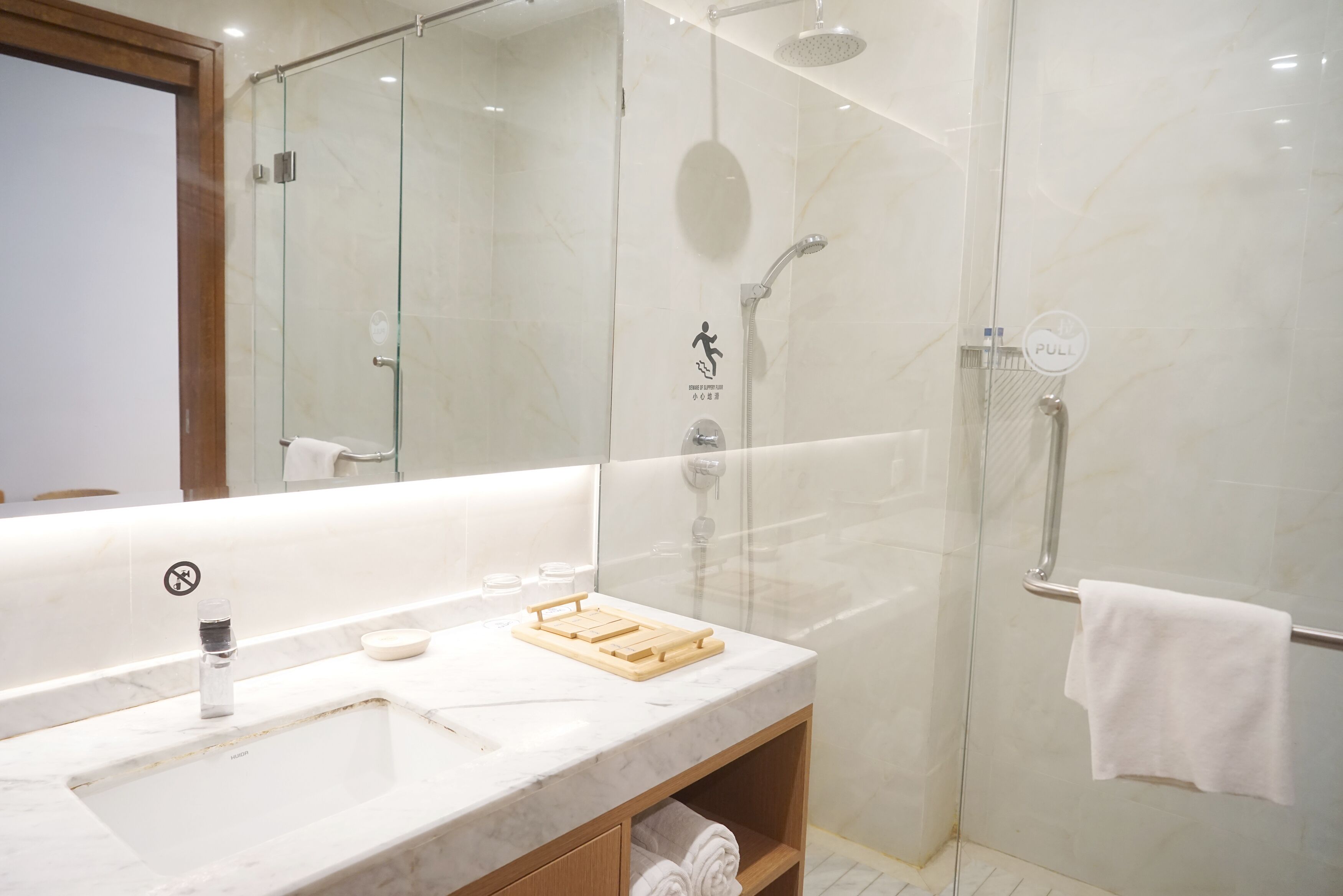 Un bagno moderno con doccia vetrata, lavabo in marmo e porta asciugamani.