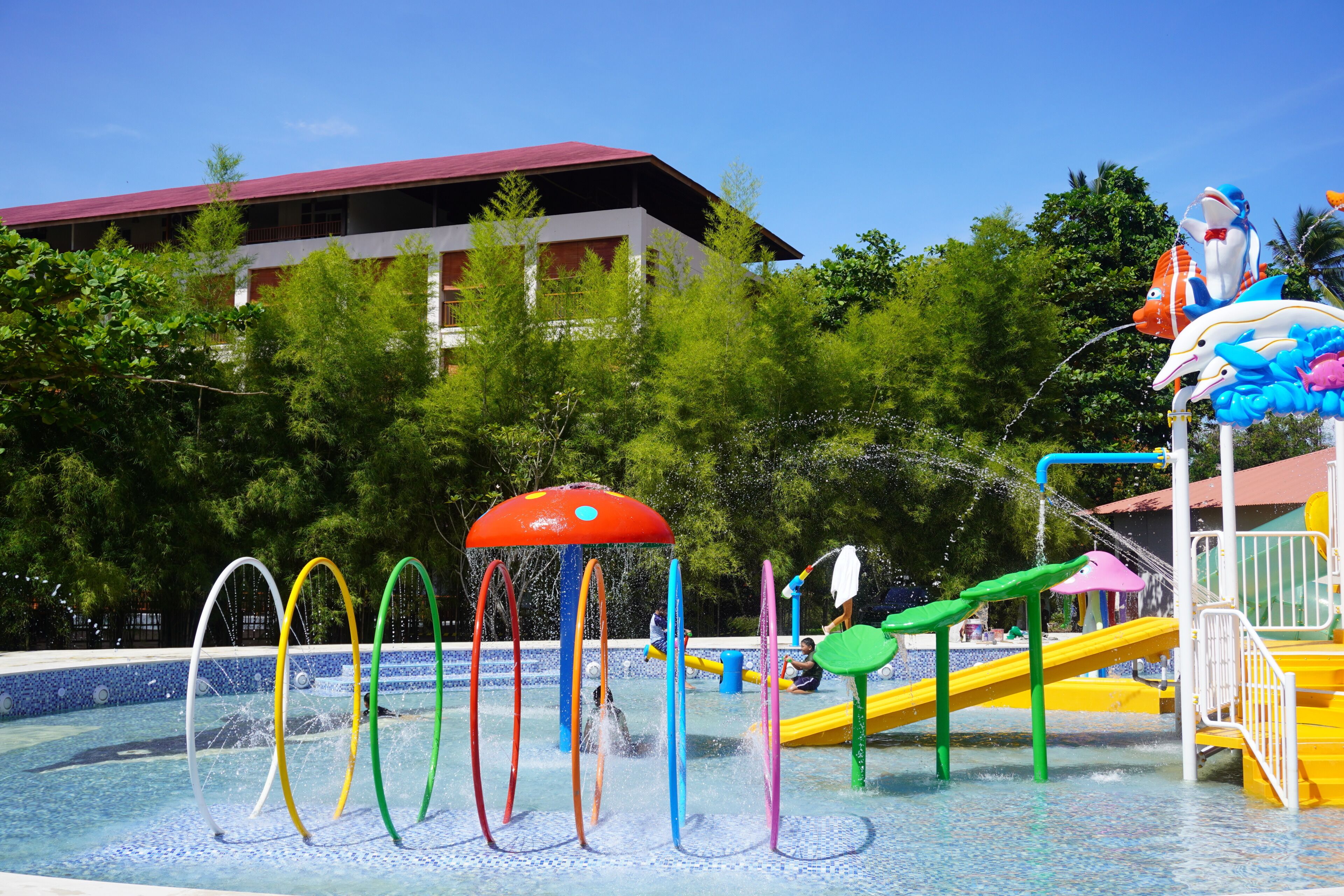 A water park with a pool, slides, and a building in the background.