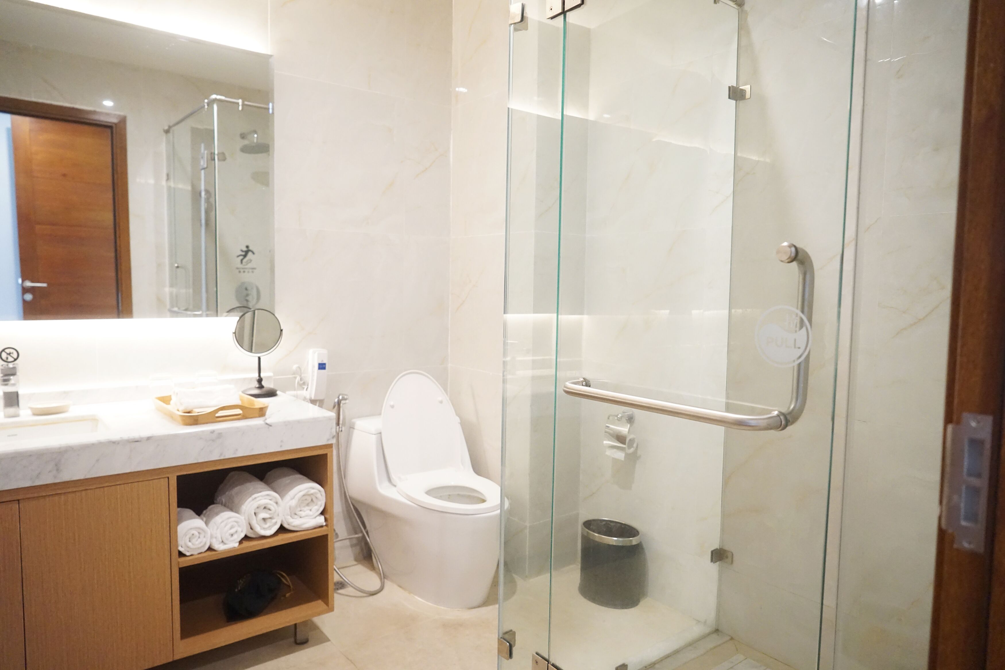 Une salle de bain moderne avec une douche à parois de verre, des toilettes et un meuble-lavabo avec des serviettes.
