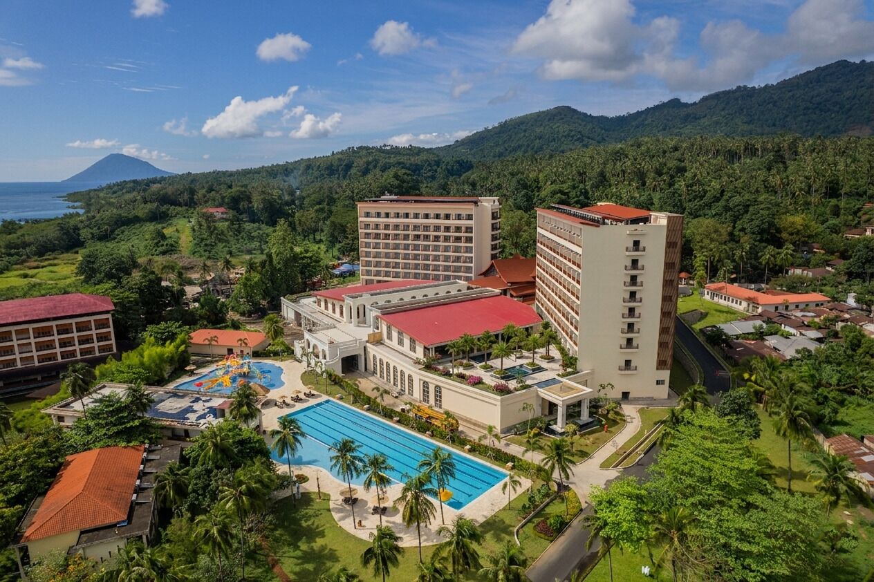 A resort with multiple buildings, a swimming pool, and a mountainous backdrop.