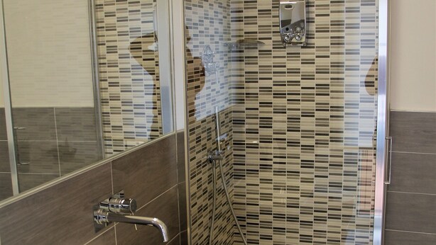 A modern bathroom with a white sink, a glass shower enclosure, and a tiled backsplash.
