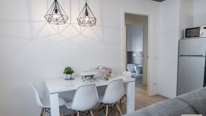 A modern kitchen with a white countertop, two pendant lights, and a microwave on the counter.