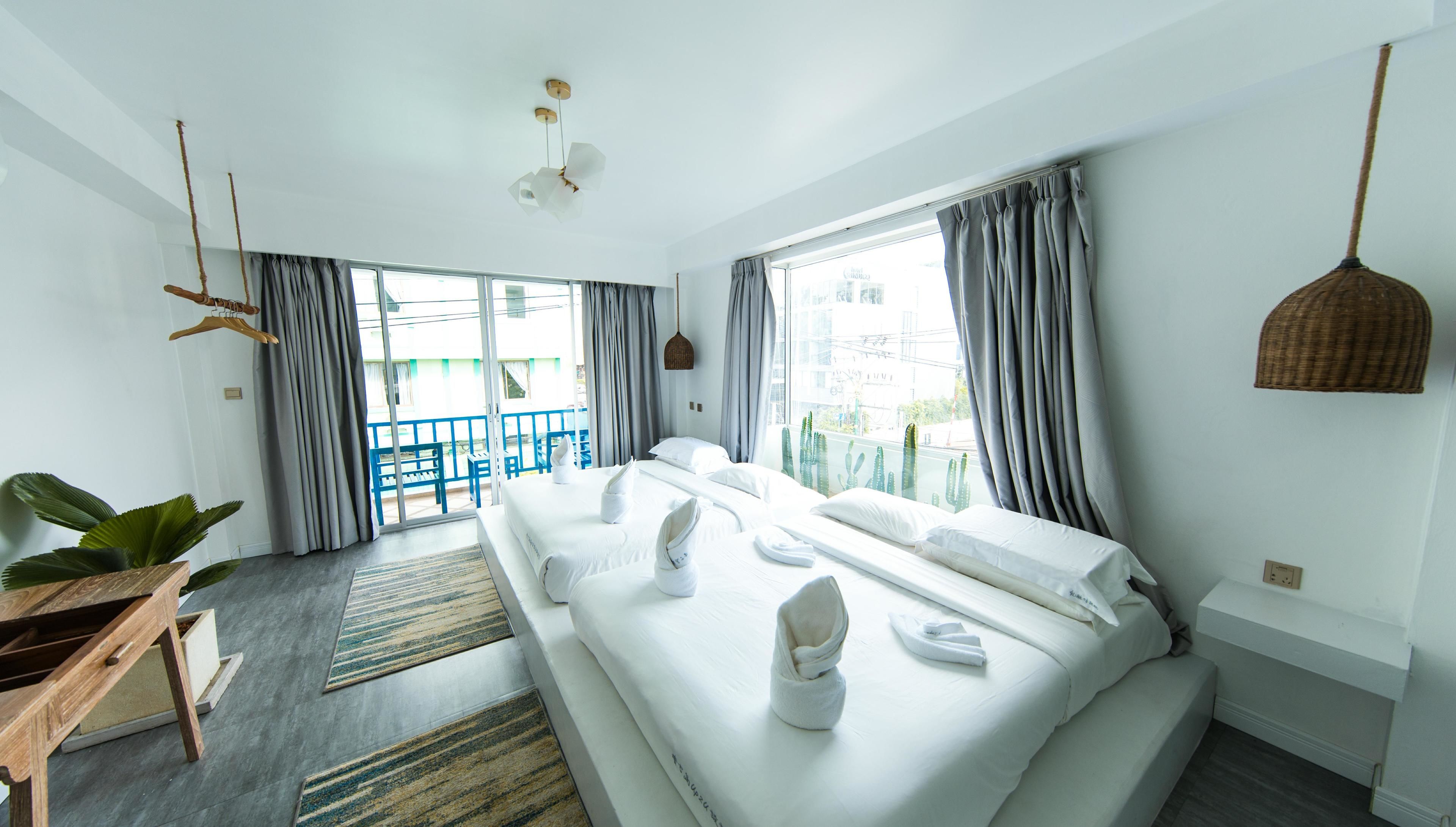 A modern hotel room with a large bed, a balcony, and a view of the city.