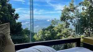 A bed with a view of a mountainous landscape through a glass window. - Romance Valley (Hildummulla)