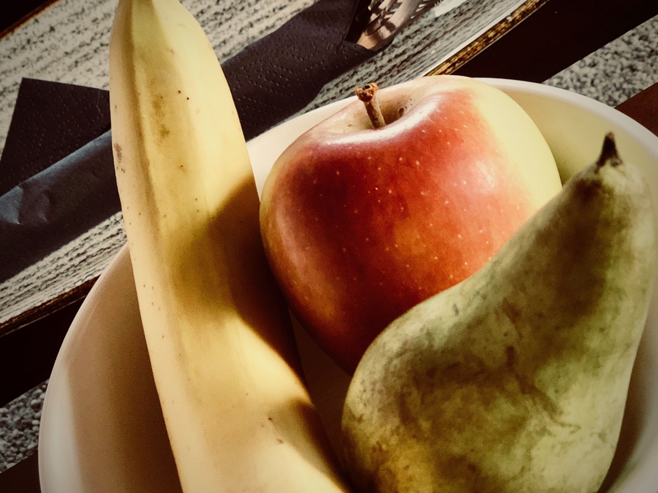 Een kom met een banaan, een appel en een peer.