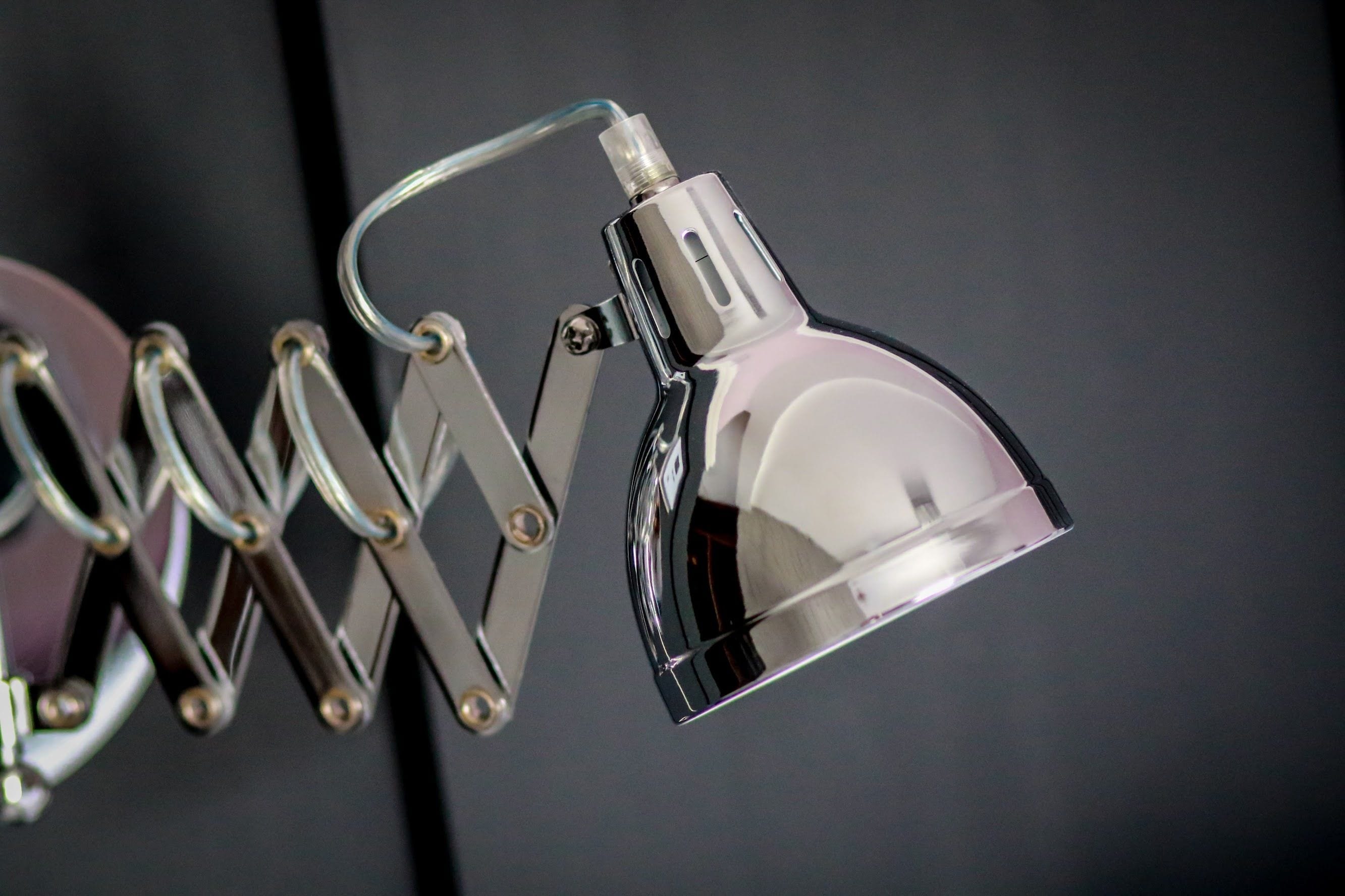 Eine metallische, verstellbare Schreibtischlampe mit einer reflektierenden Oberfläche und einem flexiblen Arm.