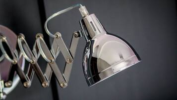 Eine metallische, verstellbare Schreibtischlampe mit einer reflektierenden Oberfläche und einem flexiblen Arm.