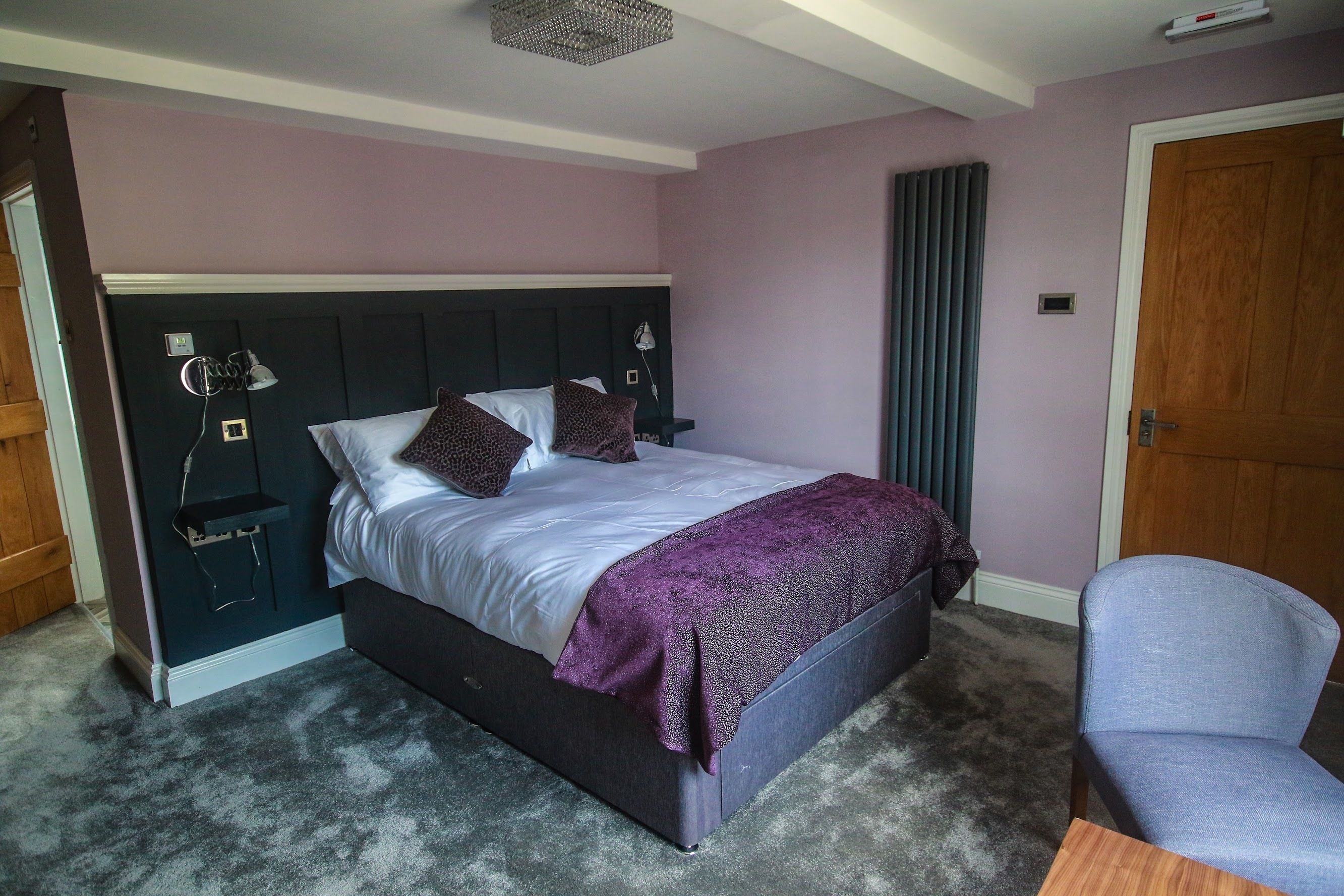 A bedroom with a bed, bedside tables, a chair, and a door.