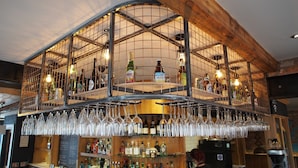 Zona de bar con varios niveles, estantes llenos de botellas y copas.