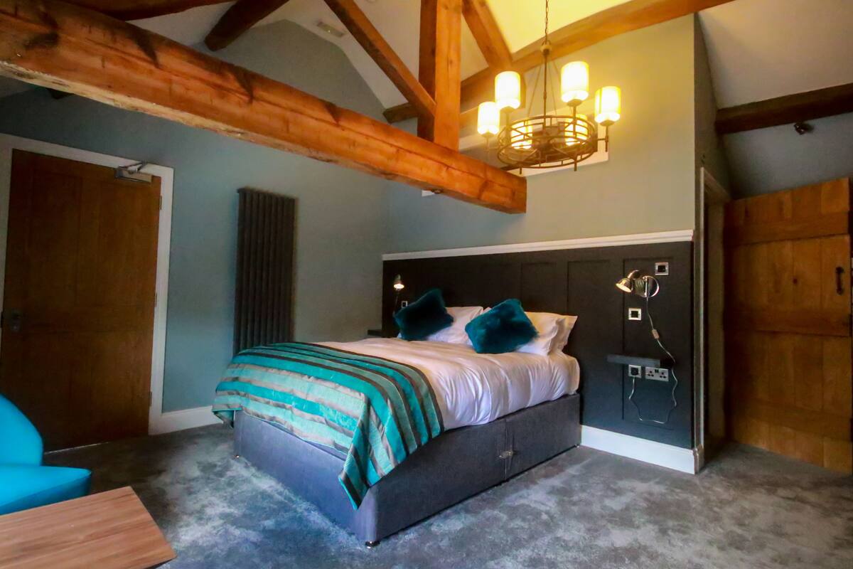 Un dormitorio con cama, una silla, un radiador y vigas de madera.