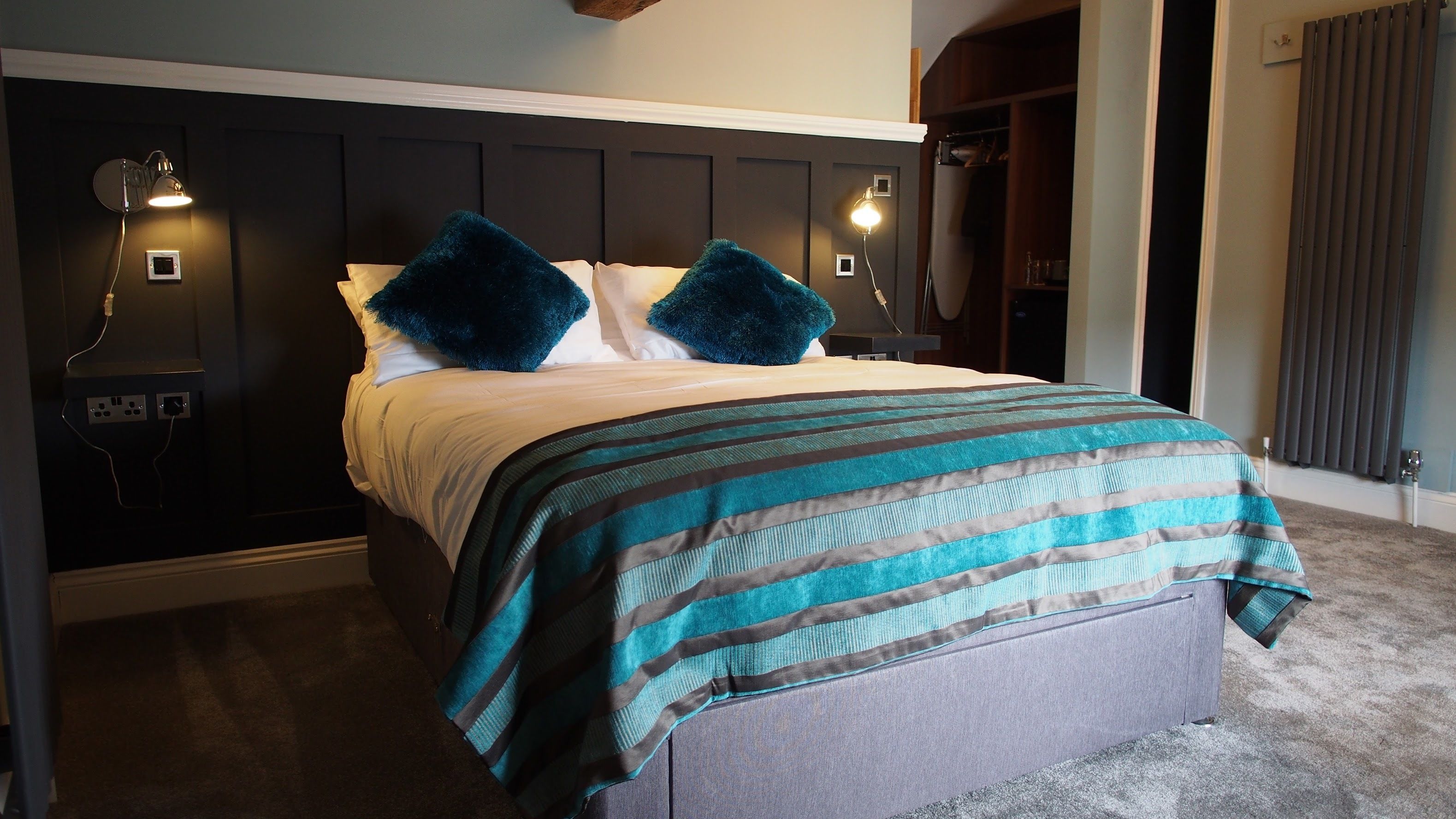 Ein ordentlich gemachtes Bett mit einer gestreiften Decke, zwei Kissen und zwei Wandlampen.