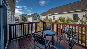 Une terrasse en bois, dotée de mobilier d’extérieur et offrant une vue sur les maisons voisines.