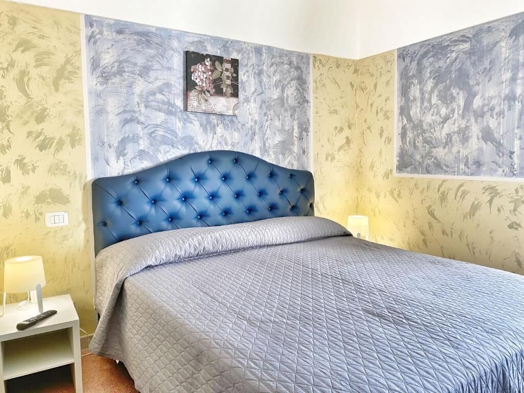 A bedroom with a tufted headboard, a quilted bedspread, and a nightstand with a lamp.