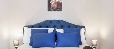 A neatly made bed with blue and white bedding, a tablet, and a book on the bed.