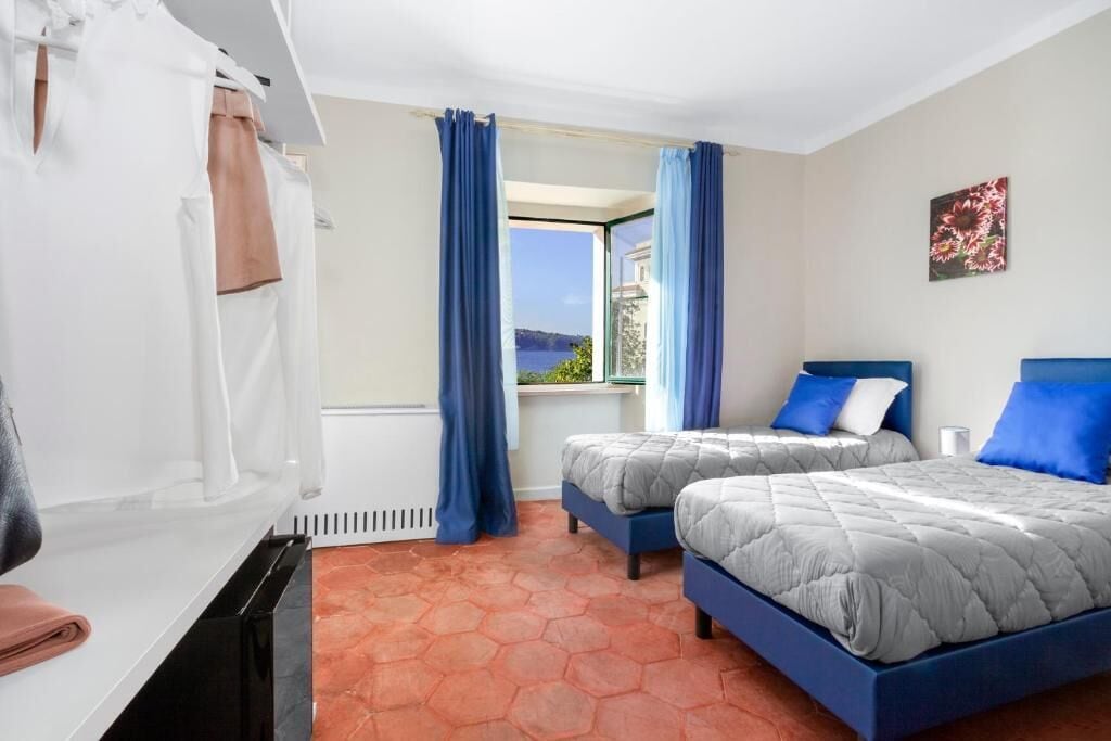 Habitación de hotel con dos camas, baño y vista al mar.