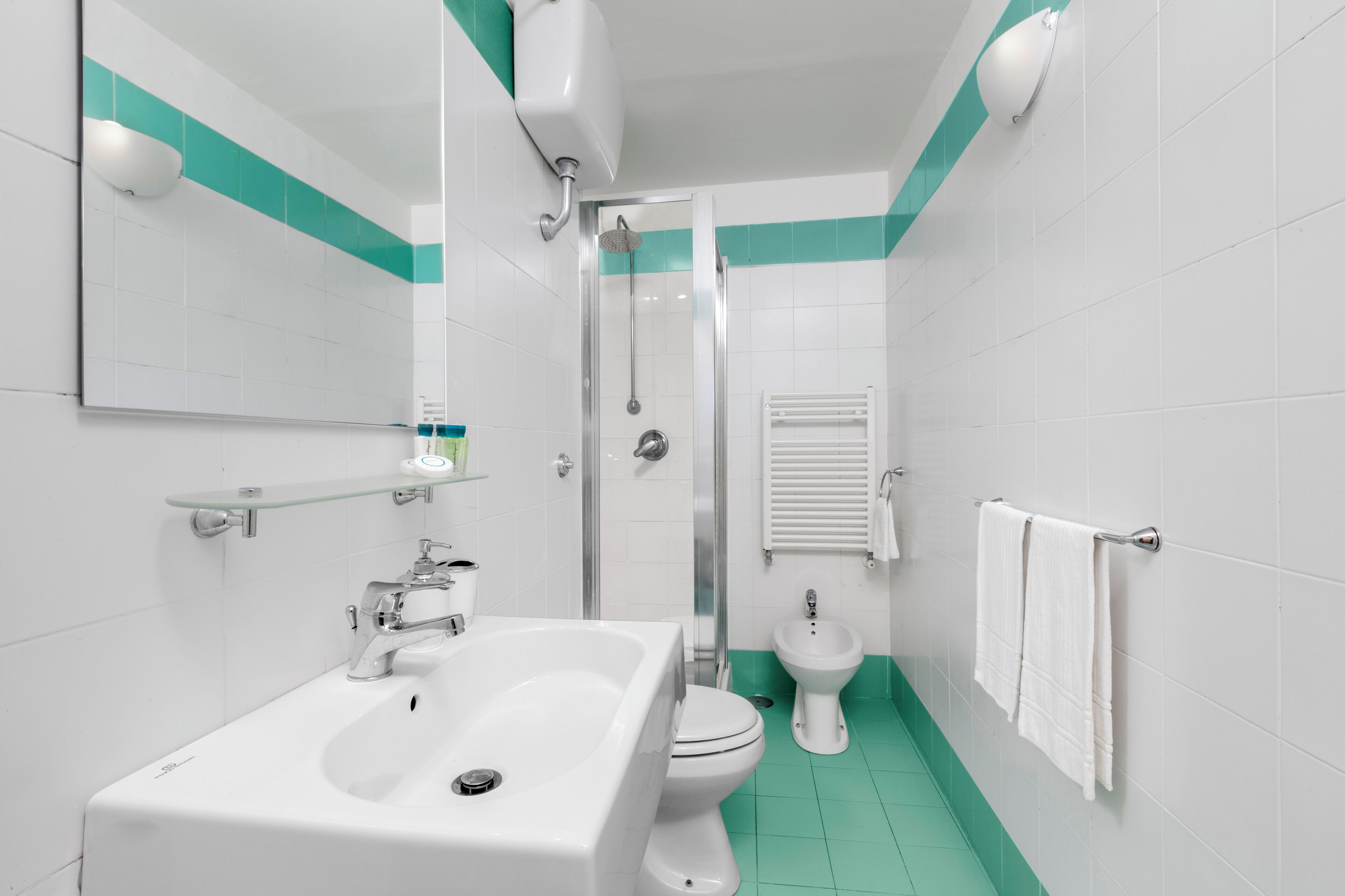 A bathroom with a sink, toilet, bidet, and a glass shower enclosure.