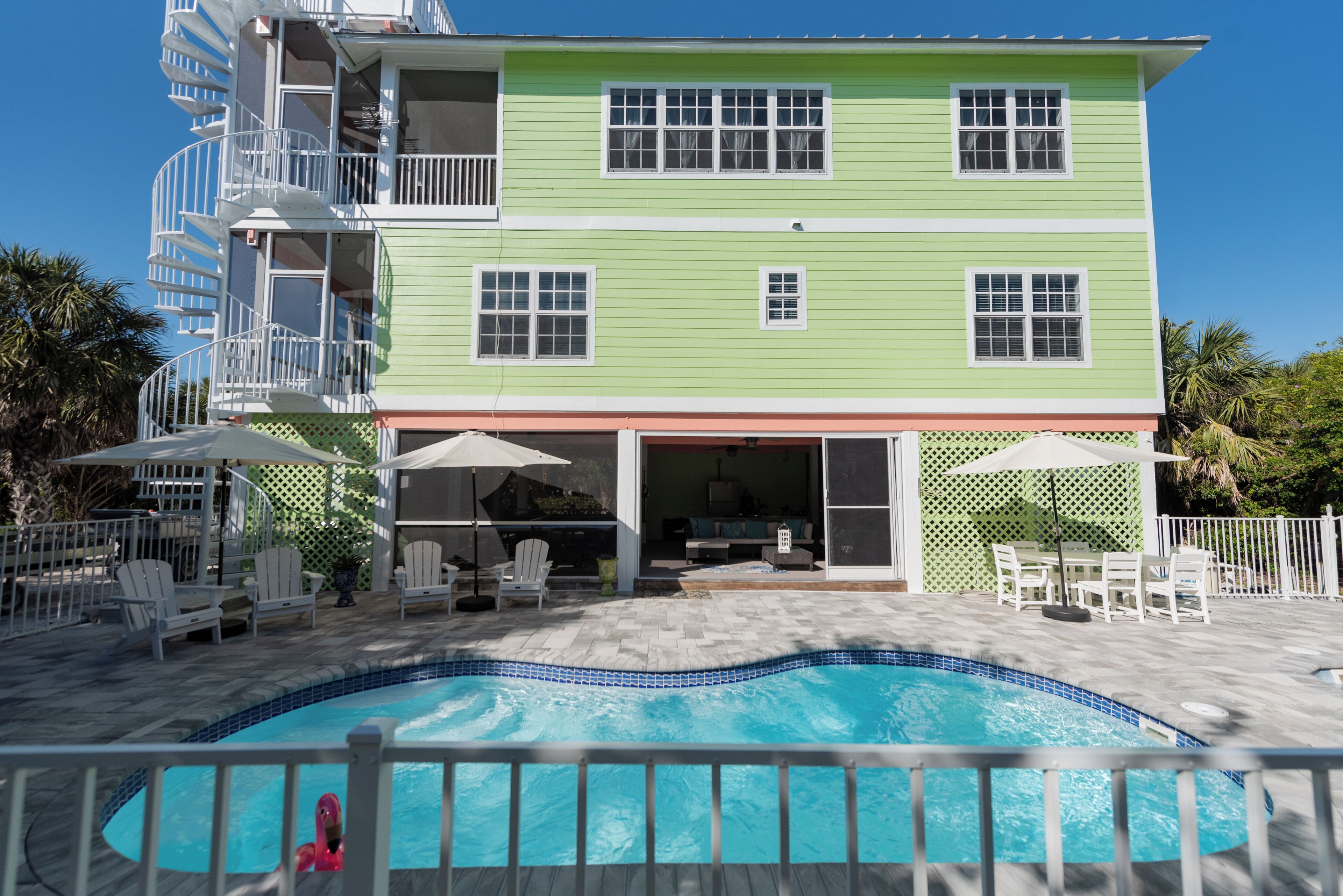 A two-story building with a swimming pool, outdoor seating, and a covered patio area.
