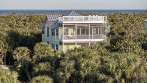Een tweelaags huis met een balkon, omgeven door weelderige begroeiing.