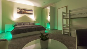 A bedroom with a bunk bed, a bedside table with a plant, a bed with a dark-colored comforter, and a painting on the wall. - Penmoor Chance - Old Town (Bratislava)