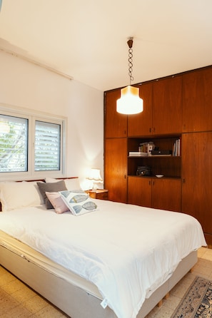 Un dormitorio con cama, armario de madera y mesita de noche con lámpara.