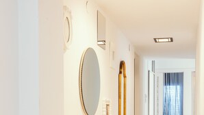 Un pasillo con suelo de baldosas, un espejo redondo y una puerta que da a otra habitación.