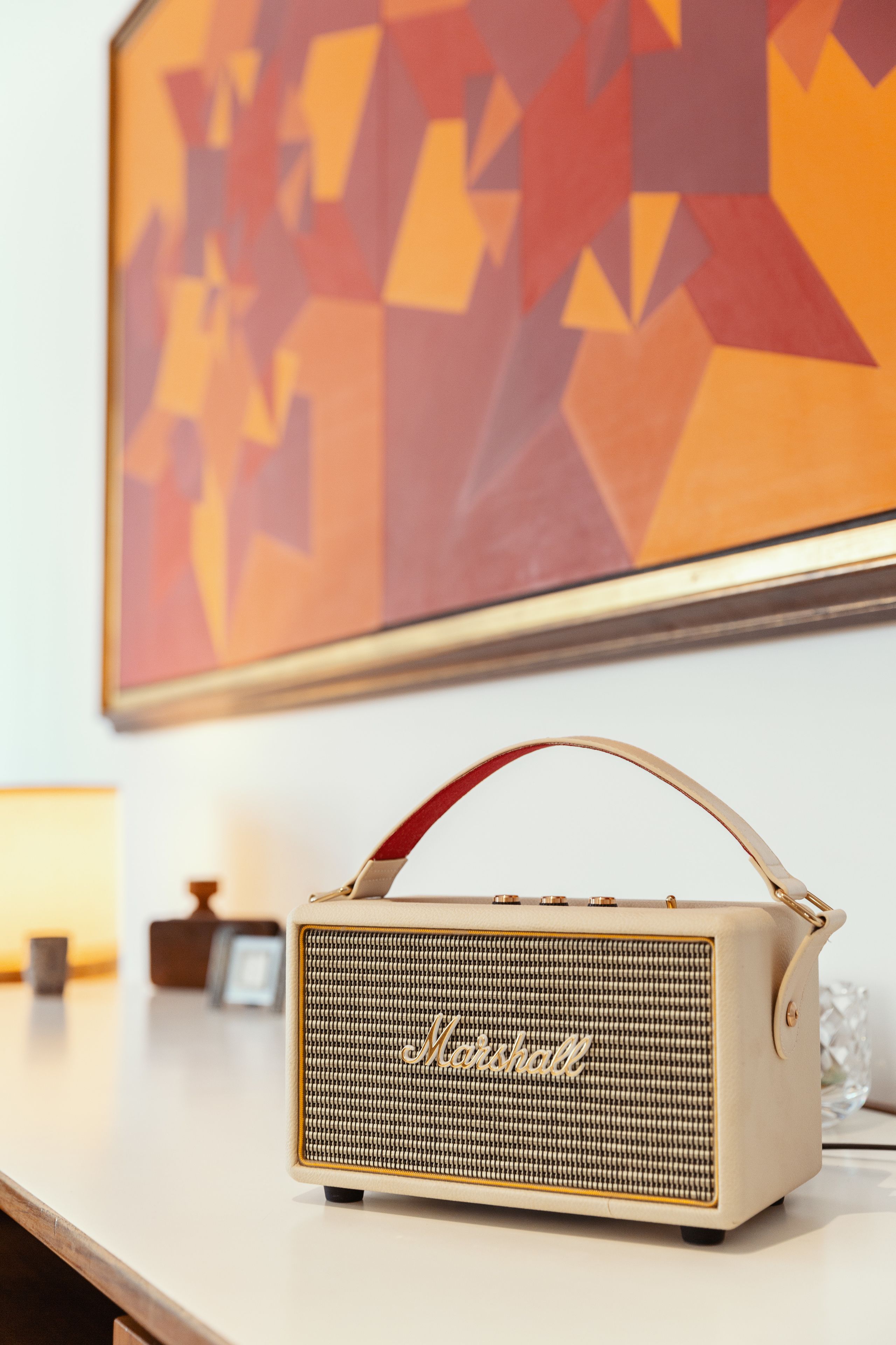 A vintage Marshall speaker on a table with a geometric painting in the background.