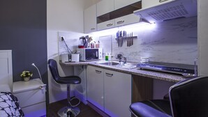 A modern kitchen with white cabinets, a microwave, a sink, and two bar stools.