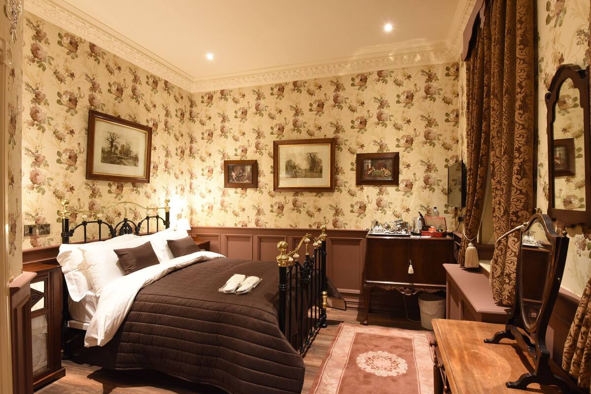 A traditional bedroom with a bed, dresser, mirror, and framed pictures on the wall.