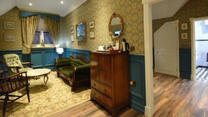 A room with a wooden dresser, two green armchairs, a wooden table, and a patterned carpet. - The Aston Tavern (Birmingham)