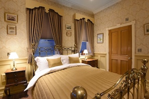 A classic bedroom with a four-poster bed, ornate curtains, and a wooden door. - The Aston Tavern (Birmingham)