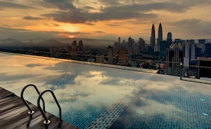 Una piscina infinita con un horizonte urbano de fondo.