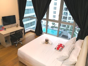 Habitación de hotel con cama, escritorio, silla, televisor y vista a una piscina.