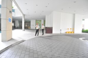 Entrada de un edificio moderno con dos guardias de seguridad, un mostrador de recepción y un camino despejado.