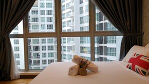 Ett hotellrum med ett stort fönster, en välordnad säng och utsikt över höga byggnader.