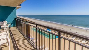A balcony with a view of a beach and a pool. - Bring Your Family to Our Gorgeous Oceanfront Condo (Myrtle Beach)