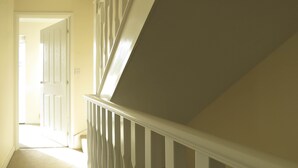 Eine Treppe mit weißen Geländern führt zu einer Tür oben.