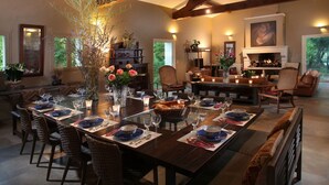 Uma sala de jantar com uma mesa comprida posta para refeição, cercada por cadeiras de vime.