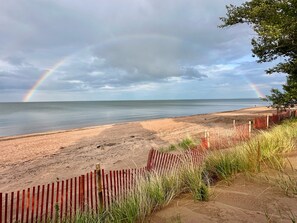 A beach with a wooden fence and grass in the foreground.