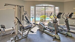 A gym with cardio machines, weight machines, and a large window overlooking a pool. - Ultra-Clean, Designer Condo. Walk to grocery, restaurants, coffee, and shopping! (Scottsdale)