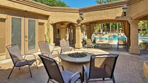 An outdoor patio area with a fire pit, lounge chairs, and a pool in the background. - Ultra-Clean, Designer Condo. Walk to grocery, restaurants, coffee, and shopping! (Scottsdale)