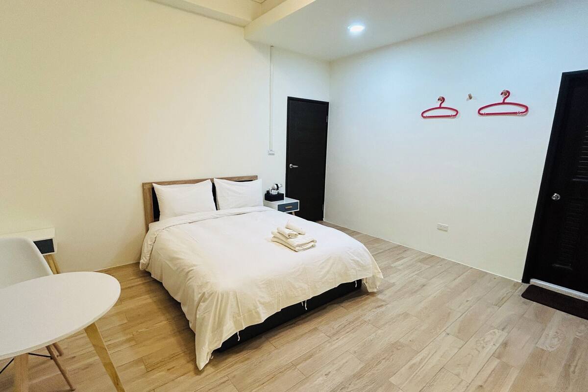 Une chambre d’hôtel avec un lit, une table de chevet, une chaise et deux portes.