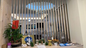 A reception desk with a wooden slat partition, a potted plant, a welcome sign, and various decorative items. - Colorful Guesthouse (Magong)
