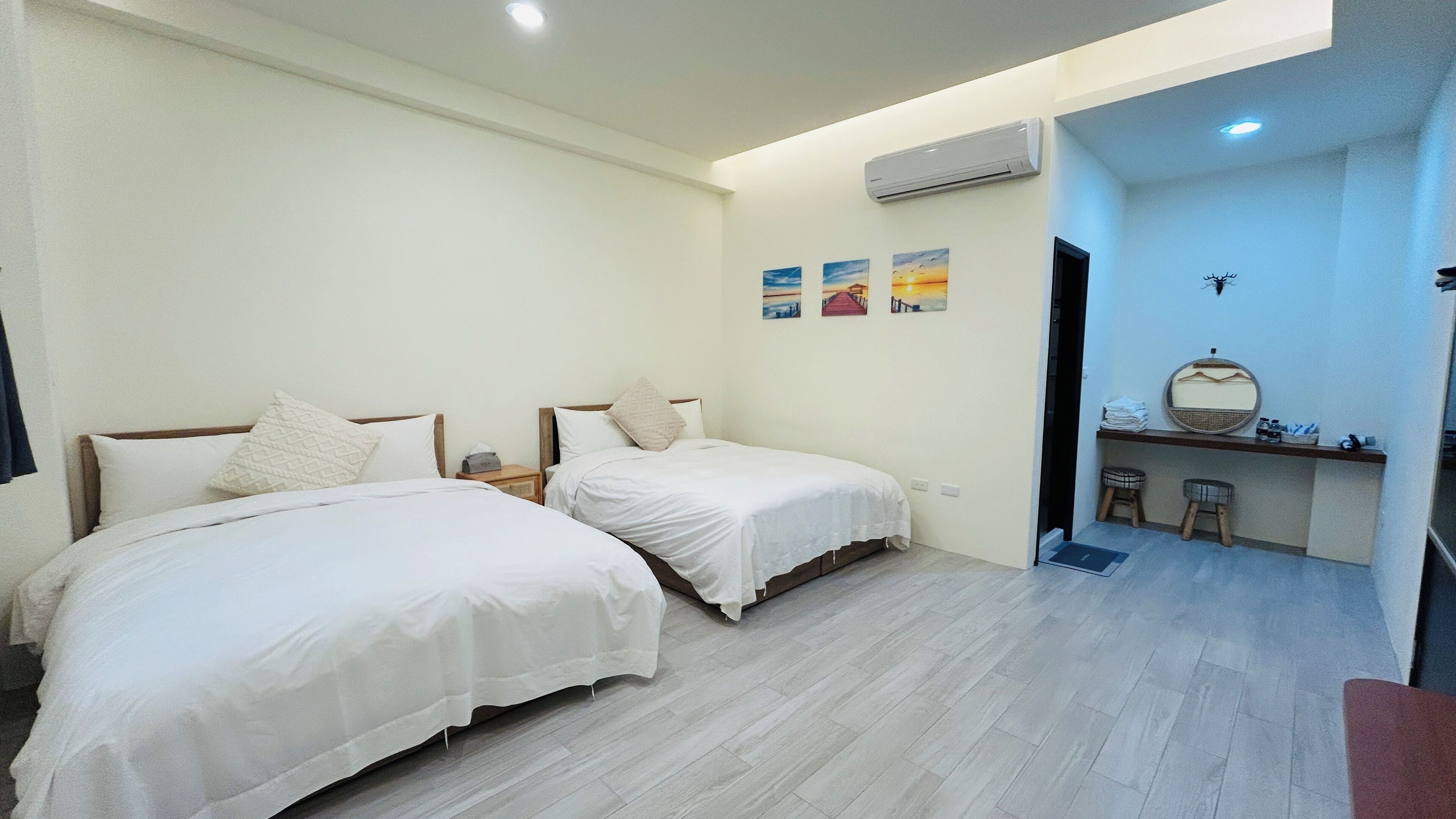 Een kamer met twee bedden, een klein bureau met spiegel en een airconditioning aan de muur.