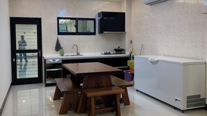 A modern kitchen with a dining area, including a wooden table and benches, a built-in stove, and an air conditioning unit. - Colorful Guesthouse (Magong)