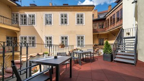 An outdoor patio area with tables and chairs, a staircase, and a building with multiple windows. - OLD TOWN -2 BEDROOM 2 BATHROOM max 8 pers (Prague 1)
