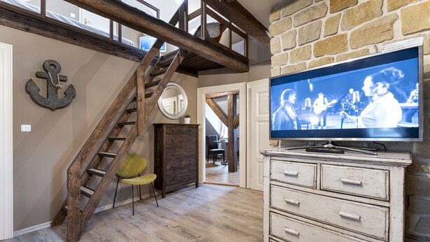 A room with a wooden staircase, a television, and a dresser. - OLD TOWN -2 BEDROOM 2 BATHROOM max 8 pers (Prague 1)