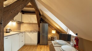 A kitchen with white cabinets, a stainless steel refrigerator, a wooden table set for two, and a small table lamp. - OLD TOWN -2 BEDROOM 2 BATHROOM max 8 pers (Prague 1)